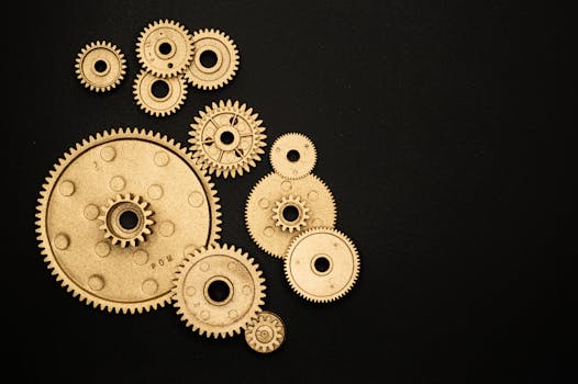 Close-up of gold gears arranged on a black backdrop, symbolizing teamwork and technology.